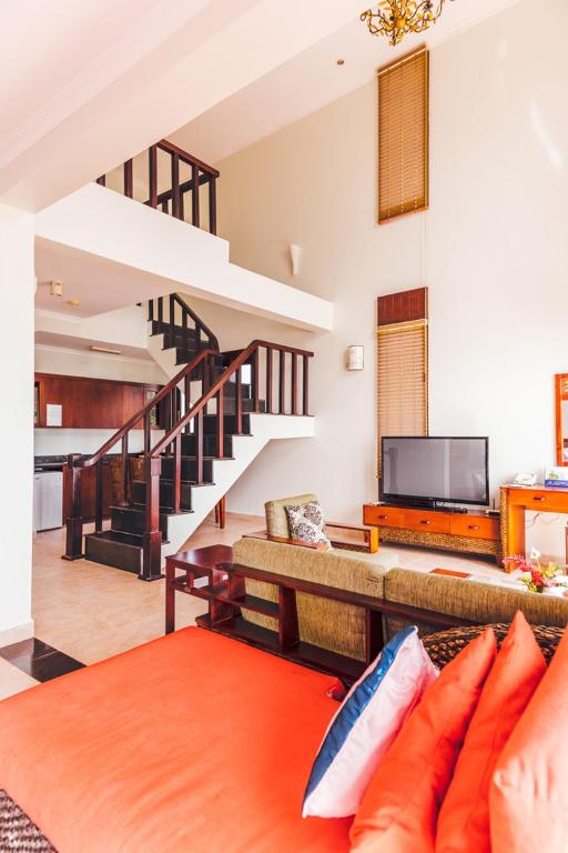 Mūsdienīgs divstāvu dzīvoklis ar viesistabu, kurā ir sēžamā zona, televizors un piekļuve virtuvei. Interjers apvieno ērtus mēbeļu elementus un gaismas, radot mājīgu atmosfēru.