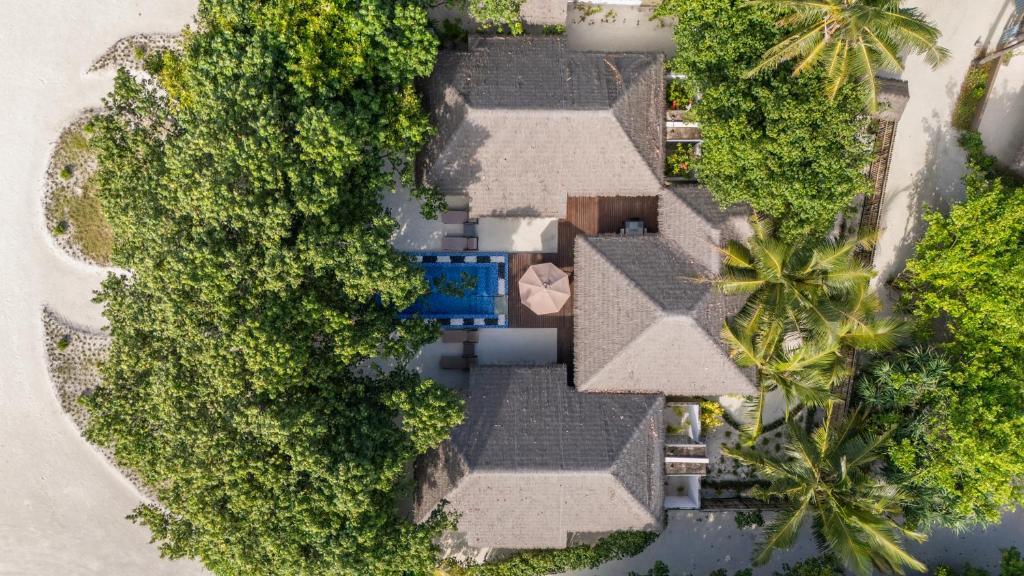 Virsējo skatu uz modernu māju kompleksu, kas ieskauts zaļojošos kokos un augos, ar privātu baseinu un terasi. Ideāla vieta relaksācijai un atpūtai.