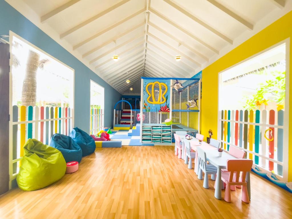 Krāsaina bērnu rotaļu telpa ar mīkstām sēdvietām, rotaļu iekārtām un zīmēšanas galdiem, kas veicina radošumu un spēles prieku. Telpa ir gaiša un draudzīga, ideāli piemērota bērnu aktivitātēm.