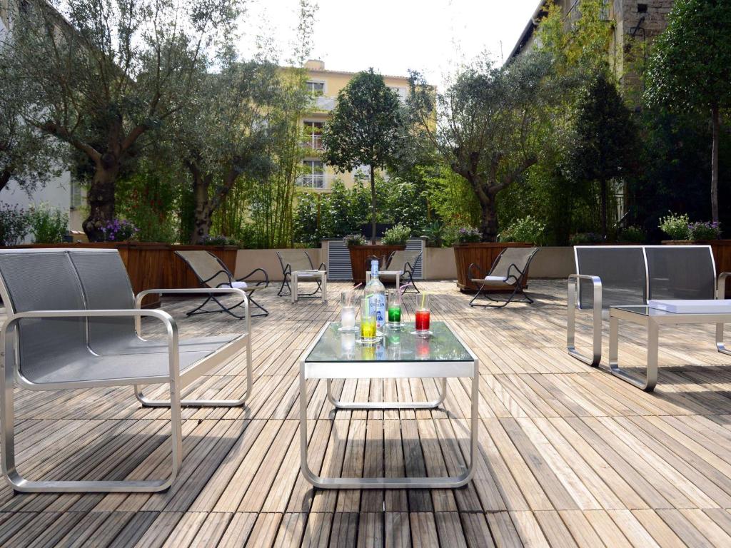 Terase ar moderniem krēsliem un stikla galdu, uz kura novietoti dzērieni, ieskauta zaļumiem un kokiem. Ideāla vieta relaksācijai un atpūtai.