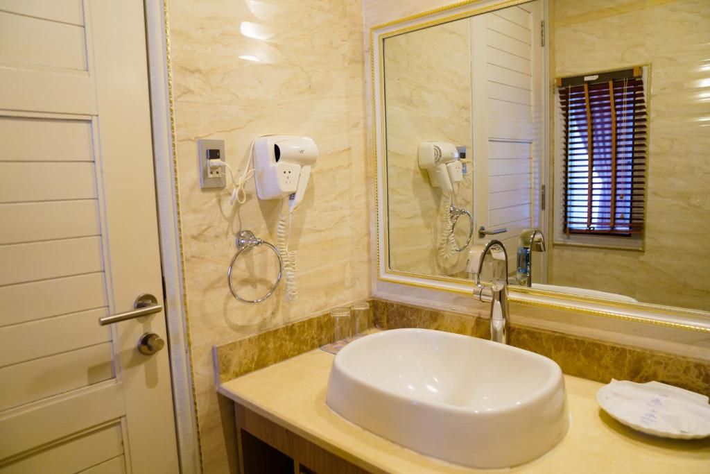 Moderns vannas istabas interjers ar skaistu izlietni, spoguli un fēnu pie sienas. Gaišas krāsas un eleganti akcenti rada patīkamu atmosfēru.