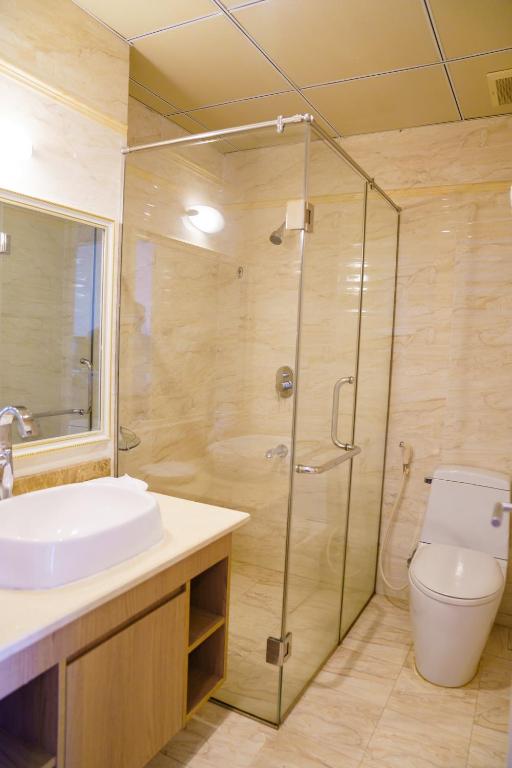 Mūsdienīga vannas istaba ar stikla dušu, baltu izlietni un tualeti, kas atrodas uz marmora grīdas.