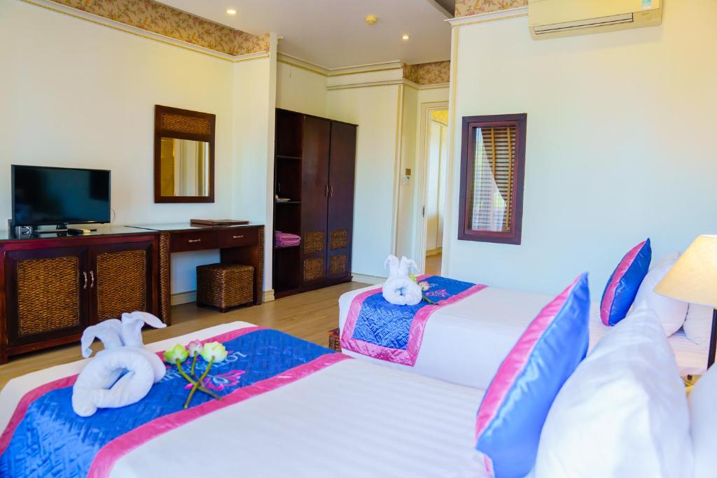 Gaismas un moderns viesnīcas numurs ar divām gultām, televizoru, rakstāmgaldu un dekoratīvām detaļām. Numurā redzami gultas dekori un ziedi, kas piešķir patīkamu atmosfēru.