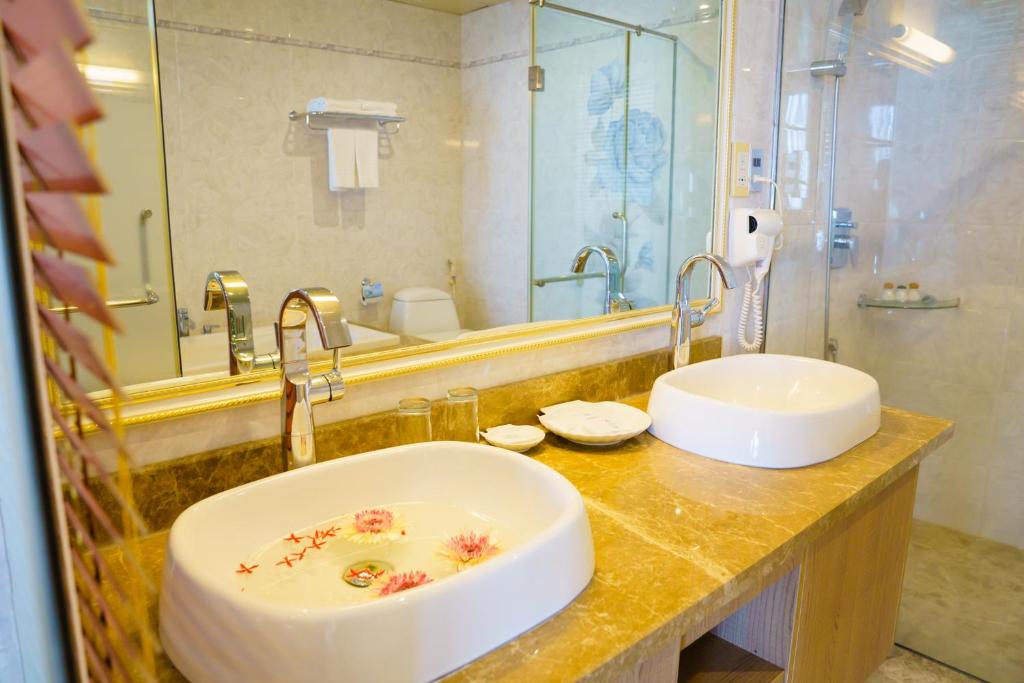 Mūsdienīga vannas istaba ar diviem izlietnēm, dekorēta ar ziediem un marmora virsmu. Vannas istabā ir duša un spogulis, radot elegantu atmosfēru.