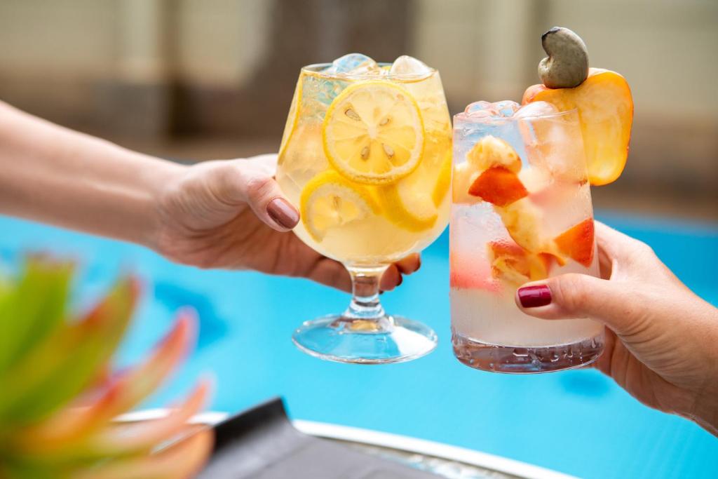 Atsvaidzinoši kokteiļi tiek pacelti, svinot brīvdienas pie baseina. Dzērieni ir dekorēti ar augļiem un ledus, radot vasarīgu atmosfēru.