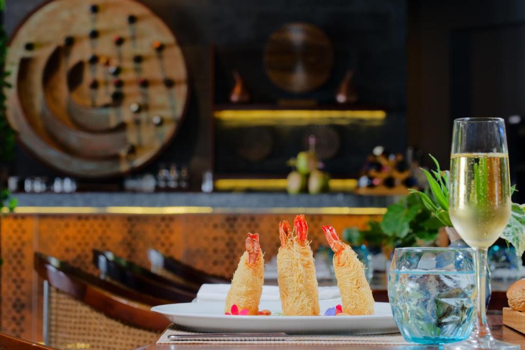 Gurķu ēdiens ar garnelēm un šampanieti, kas pasniegts eleganti noformētā restorānā, ar krāšņu interjeru un dekoratīvām detaļām.