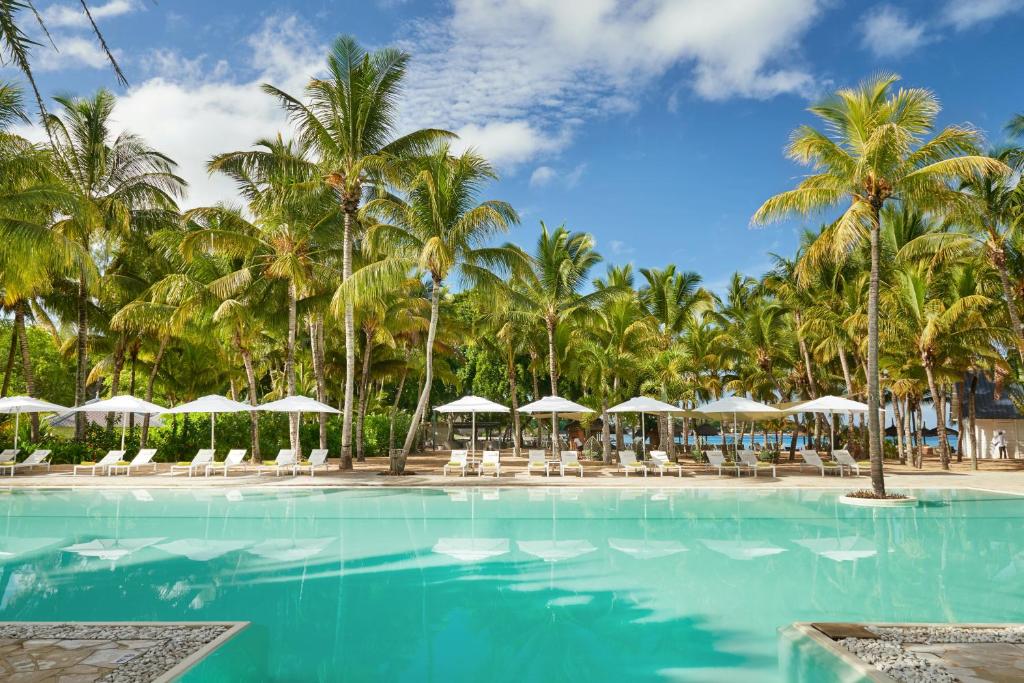 Tropu baseins ar palmām un saulessargiem, kas nodrošina atpūtu un relaksāciju pie ūdens. Ideāla vieta brīvdienām saulainā atmosfērā.