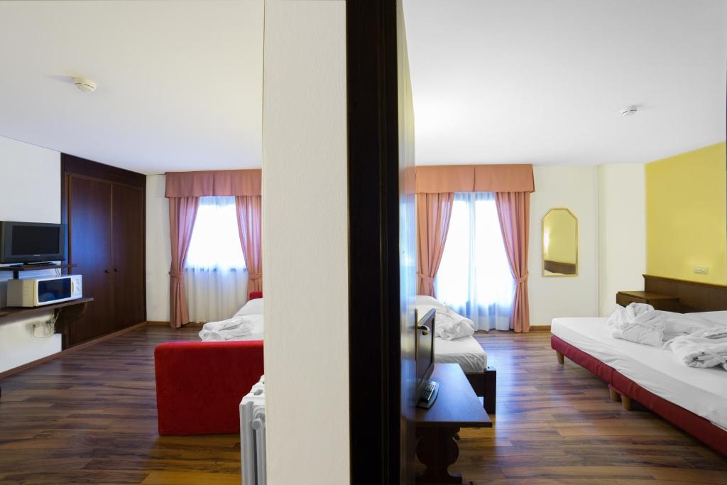 Divu viesnīcu numuru skats ar atšķirīgu interjeru, kur katrā ir gulta, televizors un logi ar žalūzijām. Numuriem ir dažādas krāsas un dekorācijas.