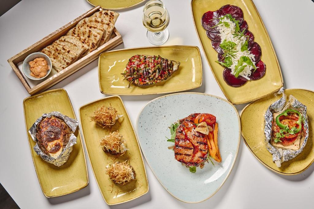 Svaigu ēdienu izvēle uz vairākiem šķīvjiem, tostarp grilēta gaļa, dārzeņu salāti un maizītes ar mērci. Ideāli piemērots maltītei ar draugiem vai ģimenes svinībām.