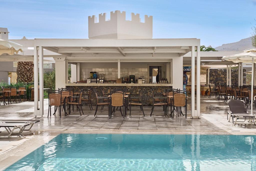 Baseins ar bāru un terasi, kurā ir brīvas vietas sēdēšanai. Apkārt atrodas zaļumi un kalnu ainava.