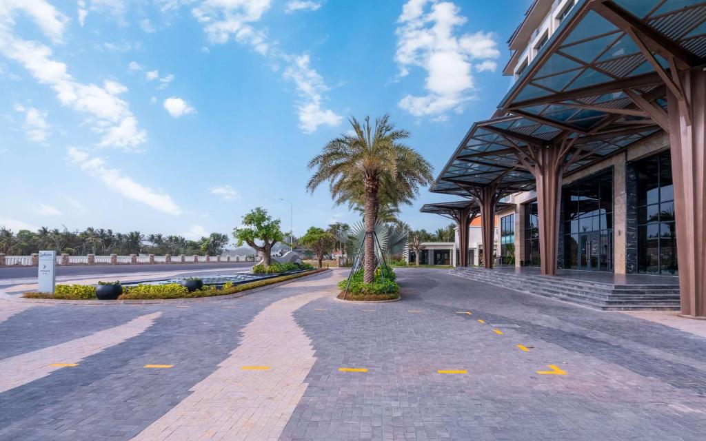 Radisson Resort Mui Ne ieeja ar palmu kokiem un modernu dizainu.