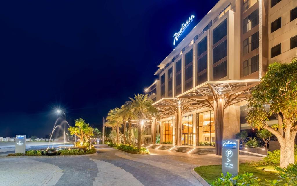 Radisson Resort Mui Ne hotel entrance at night with lights and palm trees.