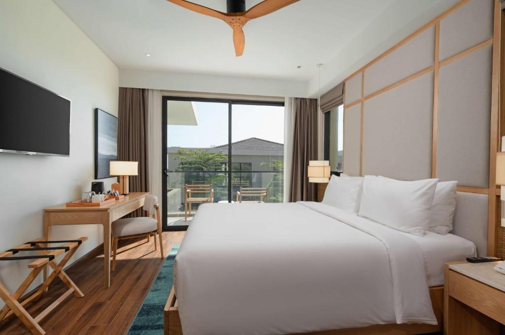 Radisson Resort Mui Ne numurs ar balkonu un skatu uz dārzu.