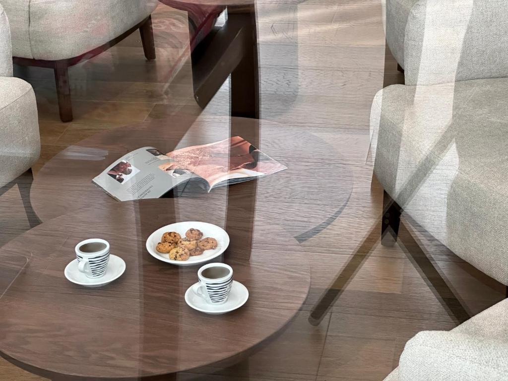 Kafijas un cepumu servēšana uz galda ar žurnālu, eleganta un mājīga interjera fons.