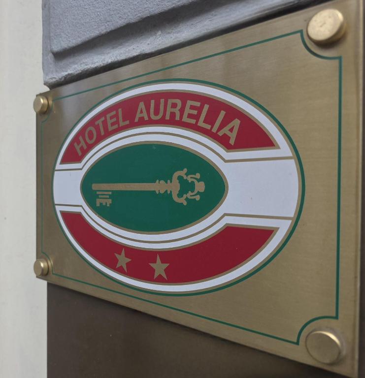 Aurelia viesnīcas zīme ar atslēgas attēlu un zvaigznēm, kas norāda uz viesnīcas nosaukumu un kvalitāti.