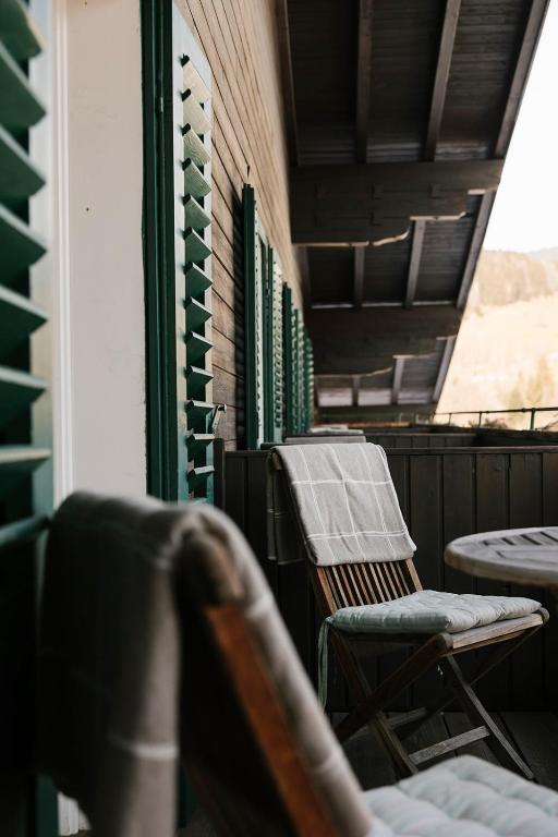 Balkons ar koka mēbelēm un zaļām logu žalūzijām, radot mierīgu un relaksējošu atmosfēru. Ideāla vieta atpūtai un sarunām.
