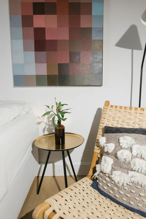 Mūsdienīga viesistaba ar abstrahētu gleznu uz sienas, koka krēslu un ziedu kompozīciju uz mazā galdiņa. Gaisīga un eleganta interjera atmosfēra.