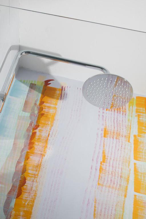 Vannas istaba ar krāsainu sienu apdari un modernu dušas galvu.