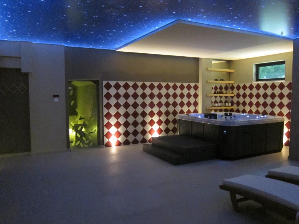 Relaksējoša spa telpa ar zvaigžņotu griestu, modernu burbuļvannu un elegantiem sarkano un baltu rombu apdarītiem sienām, kas radījuši mierīgu atmosfēru.