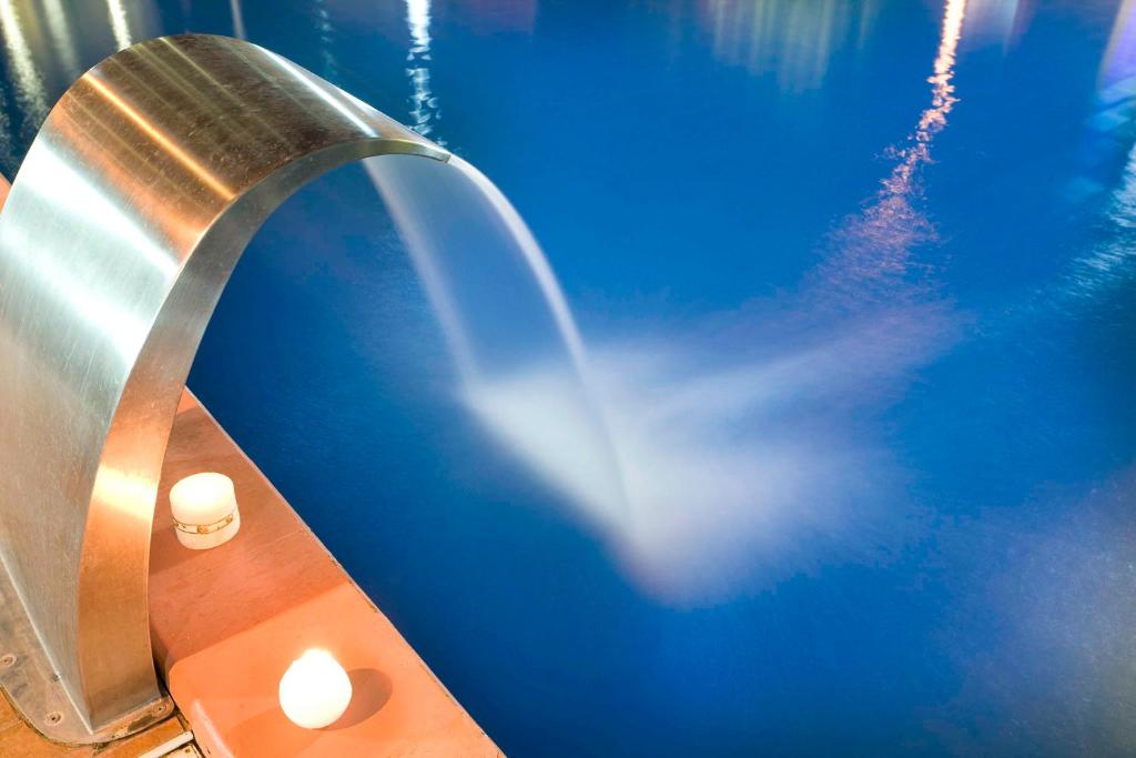 Mūsdienīgs ūdens strūklaka ar metāla dizainu, kas izplūst zilos ūdeņos, radot mierīgu un relaksējošu atmosfēru. Dvēseles mieram pievienoti sveču gaismas elementi.