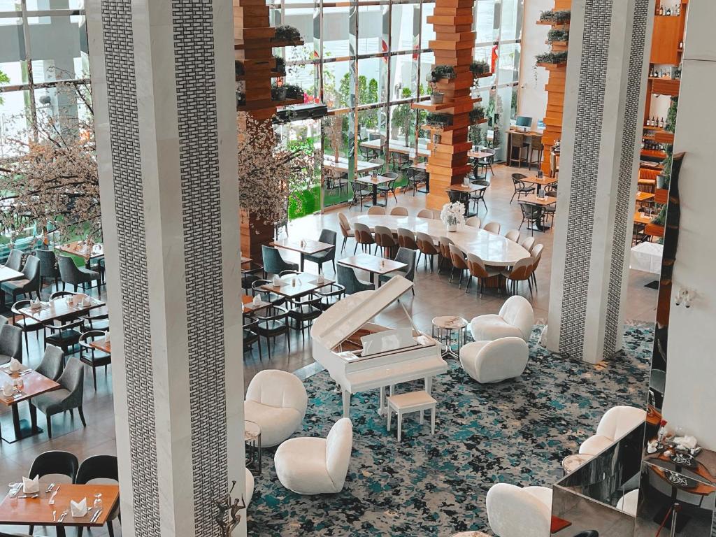 Elegantā restorāna interjers ar mūsdienīgu dizainu, balto klavieru un ziedu dekorācijām. Plašas logu ailes nodrošina dabīgu apgaismojumu un brīnišķīgu atmosfēru.