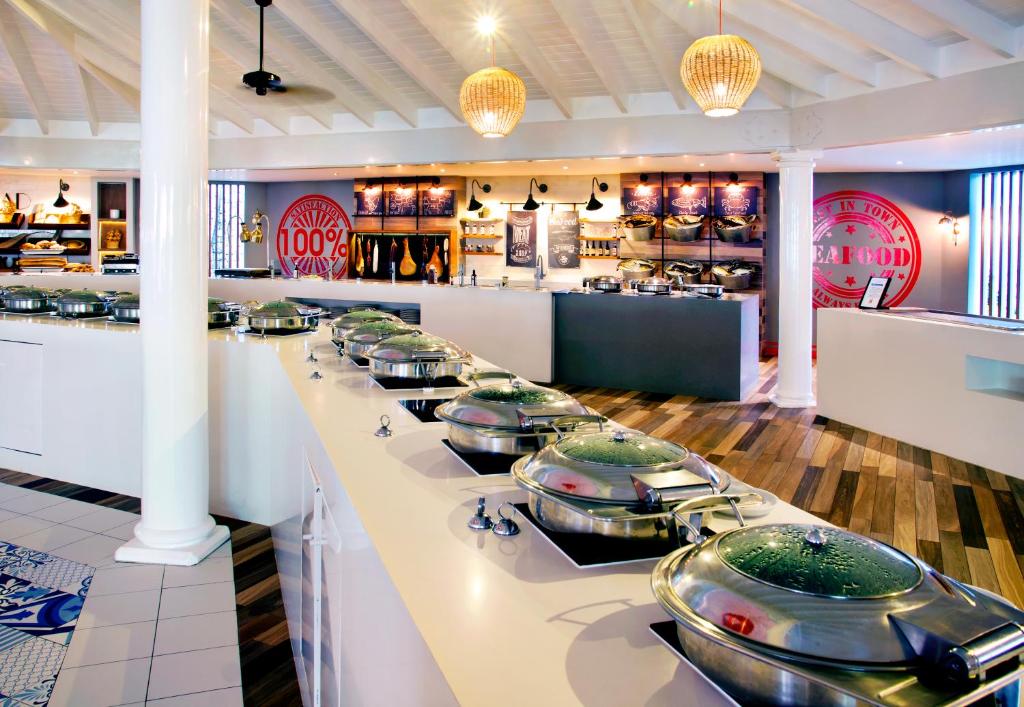 Mūsdienīgs restorāns ar plašu bufeti, kurā redzami vairāki ēdienu trauki un stilīga interjera elementi, piemēram, gaismas un dekorācijas. Ideāli piemērots gastronomiskām pieredzēm.