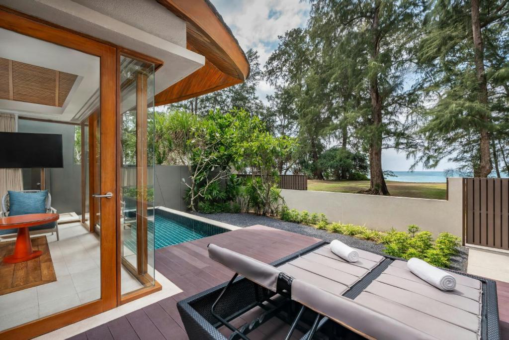 Mūsdienīga viesnīcas terase ar privātu baseinu, skatu uz dabu un jūru. Elegants interjers ar ērtu sēdvietu un koka akcentiem.