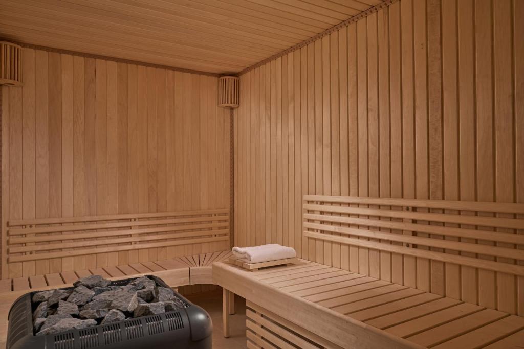 Koka saunas interjers ar koka solu un akmeņiem siltuma avotā, kas rada relaksējošu atmosfēru.