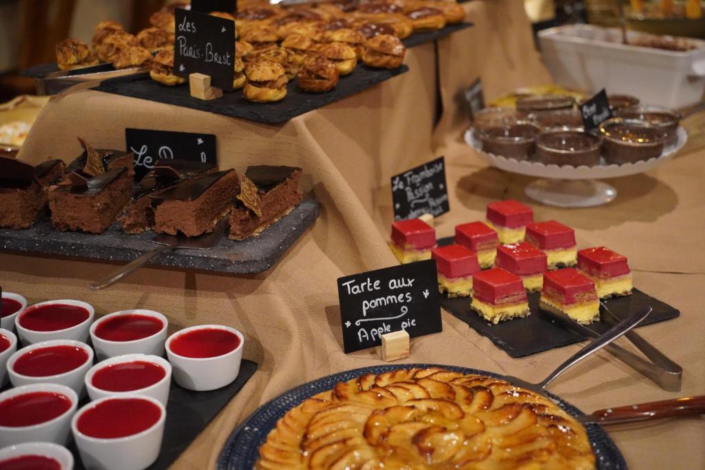 Deserts galds ar dažādām kūkām un saldumiem, tostarp šokolādes kūka, ābolu pīrāgs un krēmveida deserti. Svaigi cepti cepumi un želejas uzsver gardumu kolekciju.