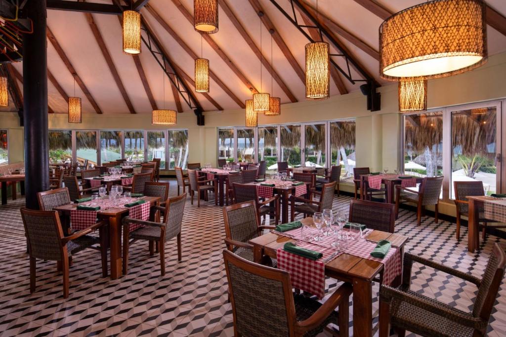 Elegantā restorāna interjers ar koka griestiem, stilīgām lampām un galdiem, kas klāti ar svinīgiem galdautiem. Lielie logi piedāvā skatu uz dabu un radījuši patīkamu atmosfēru.