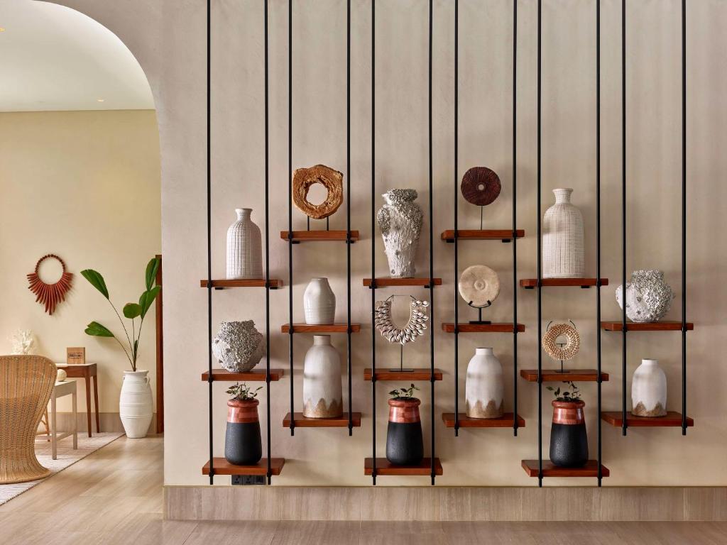 Mūsdienīgs interjers ar dekoratīvām vāzēm un mākslas priekšmetiem, kas izkārtoti uz stilizētām plauktiem. Šī telpa apvieno eleganci un radošumu, radot patīkamu atmosfēru.