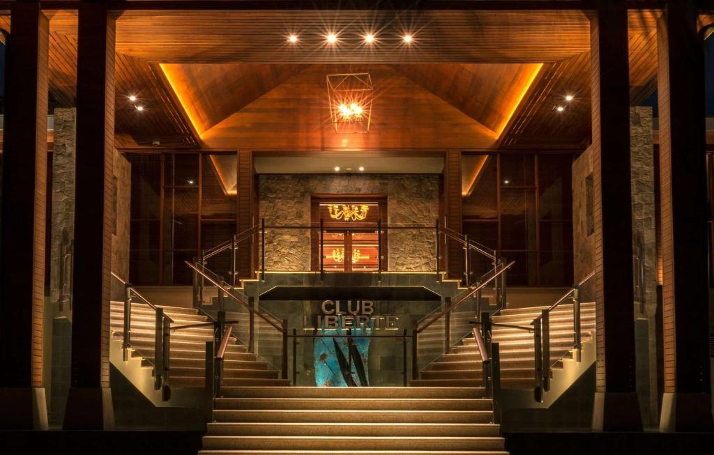 Elegants kluba ieejas dizains ar apgaismojumu un akmens elementiem. Mūsdienīgas kāpnes ved uz durvīm ar nosaukumu 