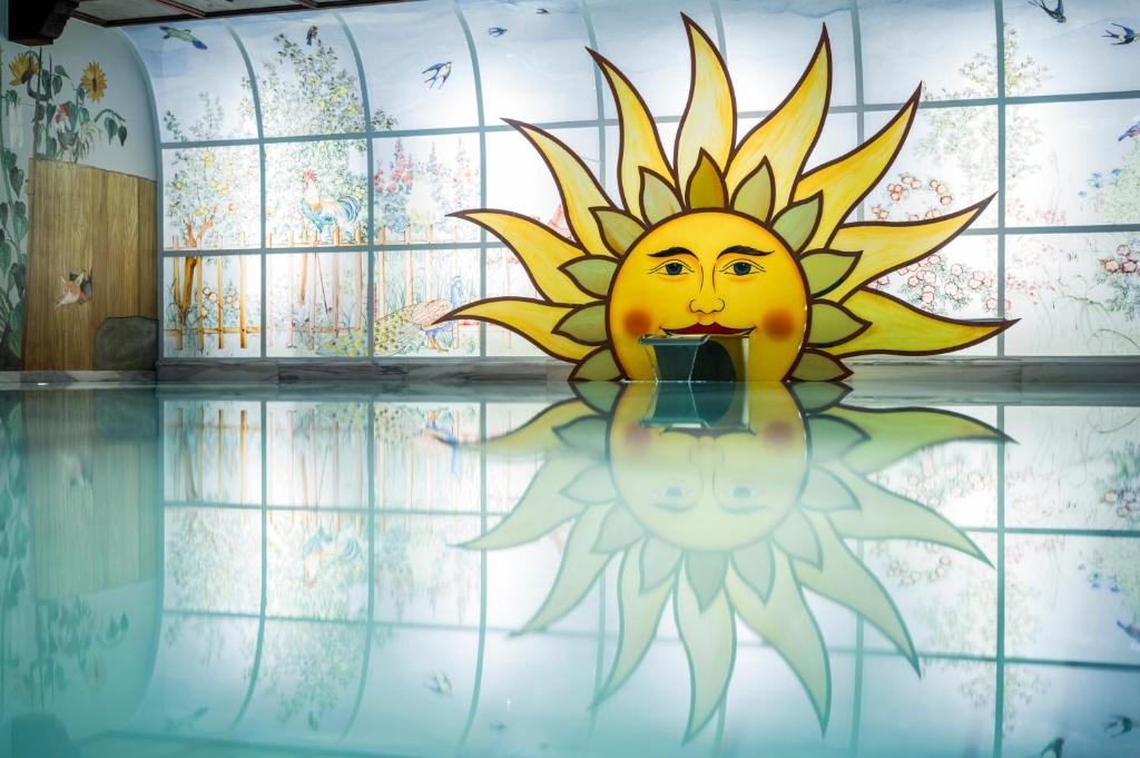 Vasaras tēma ar sauli un dabu, kas atspoguļojas ūdenī. Krāsains gleznojums ar sauli un ainavu uz fona.