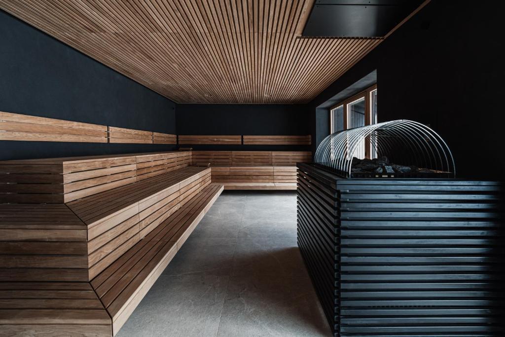 Mūsdienīga sauna ar koka un melnā metāla elementiem, kas rada relaksējošu atmosfēru. Interjers ir vienkāršs un elegants, ar koka sēdvietām un atvērtiem logiem.