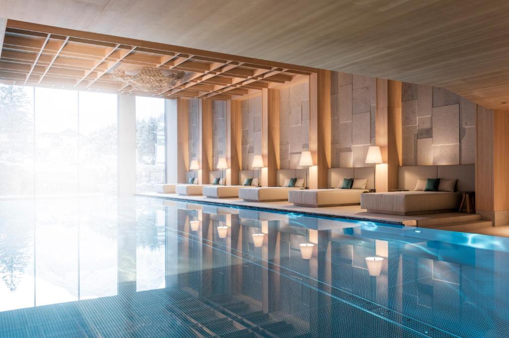 Mūsdienīgs spa ar elegantu interjeru, kas ietver baseinu un atpūtas zonas ar komfortablām gultām un mūsdienīgām lampām. Gaismas un ūdens refleksijas rada relaksējošu atmosfēru.