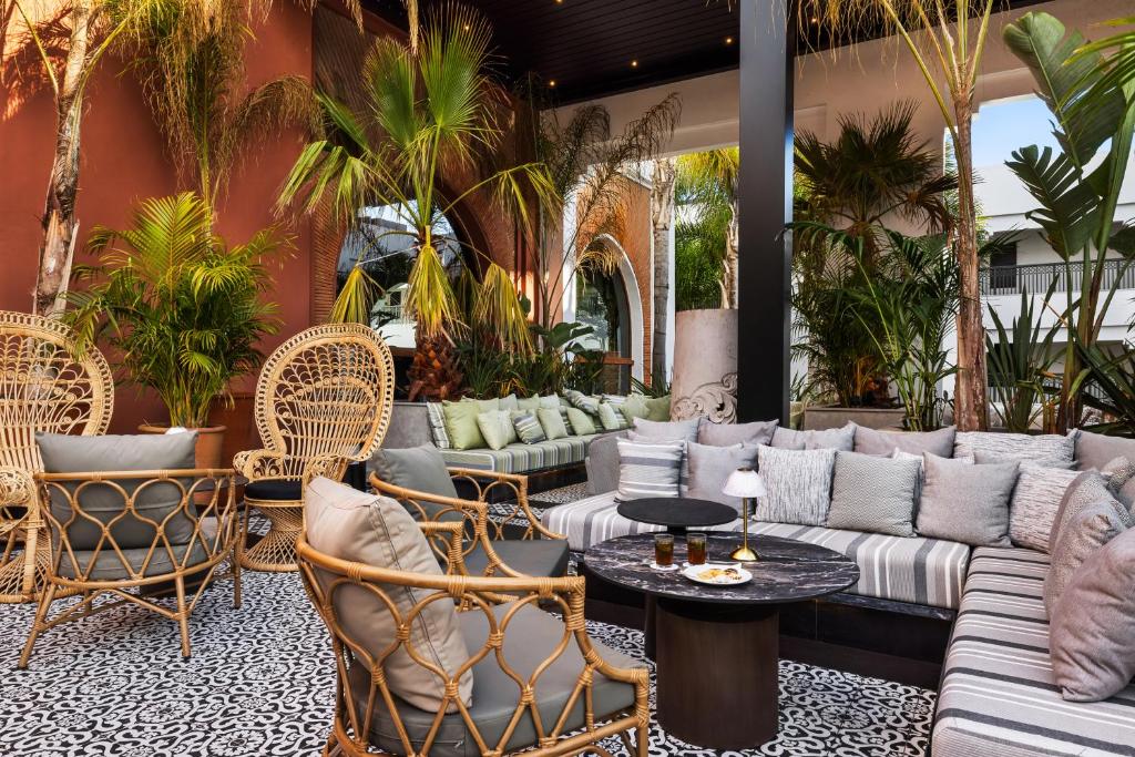 Mūsdienīgs terases interjers ar palmām, ratanam izgatavotām mēbelēm un greznu sēdvietu zonu, kas piedāvā relaksējošu atmosfēru. Ideāli piemērots atpūtai un socializēšanai.