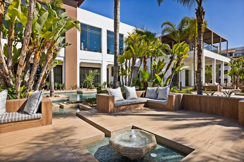 Mūsdienīgs dārza dizains ar komfortablām mēbelēm un zaļiem augiem, kas rada relaksējošu atmosfēru. Ūdens elements pievieno harmoniju un mieru ārējai telpai.