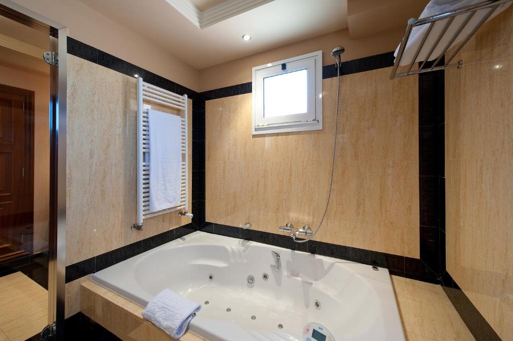 Mūsdienīga vannas istaba ar džakuzi, mīksto dvieli un siltuma radiatoru. Gaisma plūst caur logu, radot patīkamu atmosfēru.