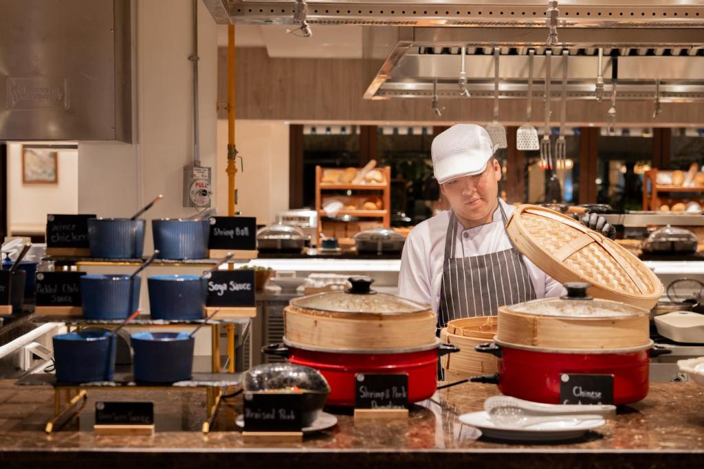 Šefpavārs gatavo ēdienus, izmantojot tvaika katlus, kam blakus ir dažādi mērču trauki. Restorāna virtuve ar modernu aprīkojumu un ērtu atmosfēru.