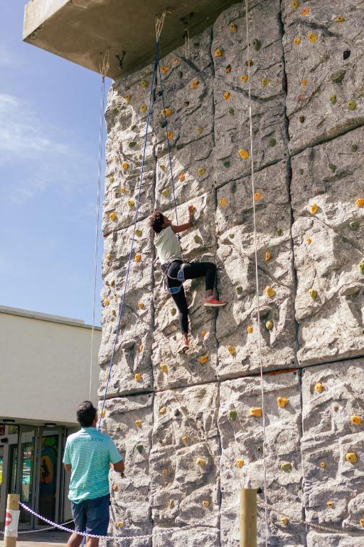 Kāpušanas sienas aktivitāte, kurā viens cilvēks kāpj augšup, bet otrs viņu vēro no apakšas. Sienā ir dažādas krāsainas turēšanas vietas.