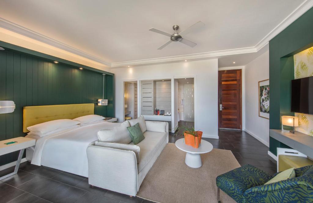 Modernas viesnīcas numurs ar zaļu sienu, ērtu gultu un atpūtas zonu. Interjers ir gaišs un elegants, papildināts ar dabīgiem elementiem un mūsdienīgu mēbelējumu.