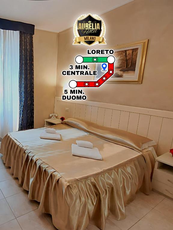 Mūsdienīgs viesnīcas numurs Milānā ar zeltainu gultas veļu, koka mēbelēm un ainavu uz sienas, kā arī informācija par tuvākajiem metro punktiem.