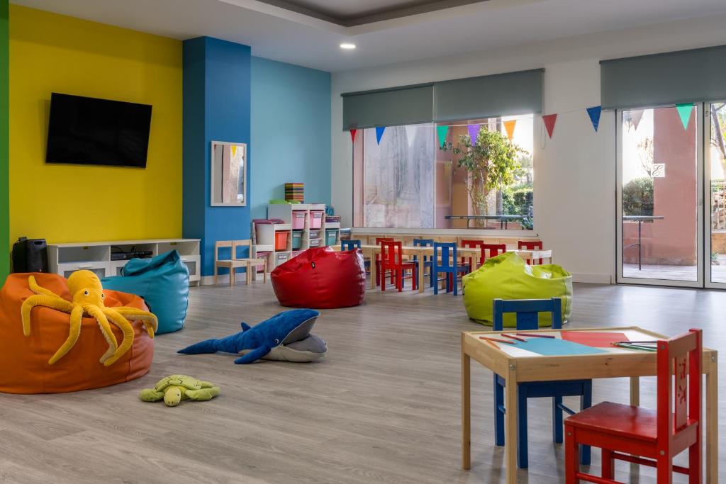 Krāsaina bērnu rotaļu telpa ar mīkstiem sēžamajiem maisiem, bērnu galds un krēsli, kā arī interjera elementi, kas veidoti jautrā stilā. Telpā ir televizors un logi, kas nodrošina dabisko apgaismojumu.