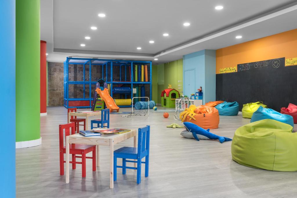 Krāsaina bērnu spēļu istaba ar rotaļu iekārtām, mīkstajām sēdvietām un galdiem. Telpā ir slidkalniņš, bērnu mājiņa un dažādas rotaļlietas.