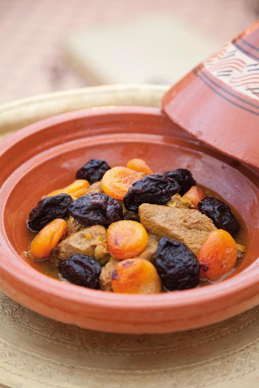 Tradicionāls marokāņu ēdiens – gaļa ar žāvētām aprikozēm un plūmēm, pasniegta keramikas traukā.