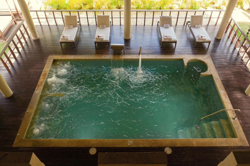 Relaksējoša atpūtas zona ar burbuļvannu un saulessargiem, kur var baudīt mierīgu atmosfēru. Apkārtne ir zaļa un labi kopta.