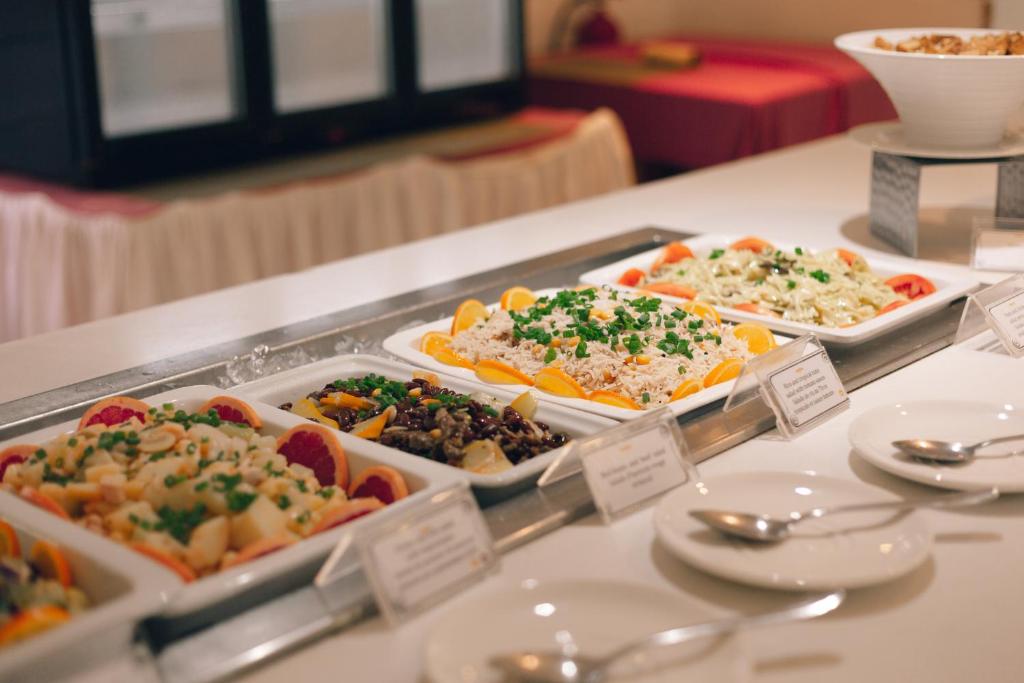 Skaista un krāsaina ēdienu bufete ar dažādām salātiem un garnējumiem, kas pasniegti baltās traukos uz galda.