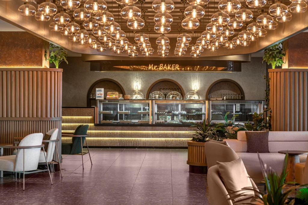 Modernā kafejnīca Vox Maris Resort ar stilīgu apgaismojumu un ēdamgaldiem.