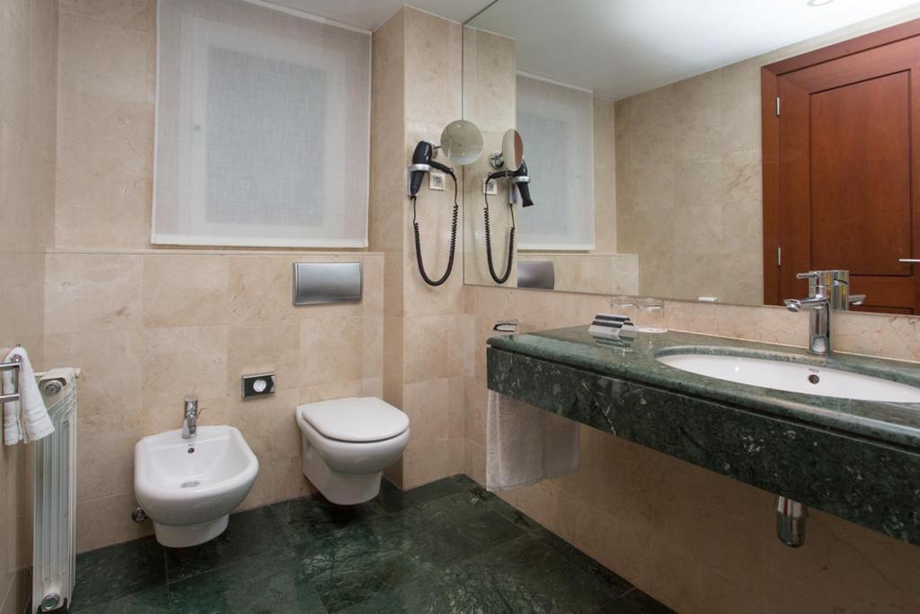 Moderns vannas istabas interjers ar marmora sienām un zaļo akmens izlietni, kas ietver tualeti un bidē. Telpa ir gaiša un stilīga, nodrošinot komfortablu atmosfēru.