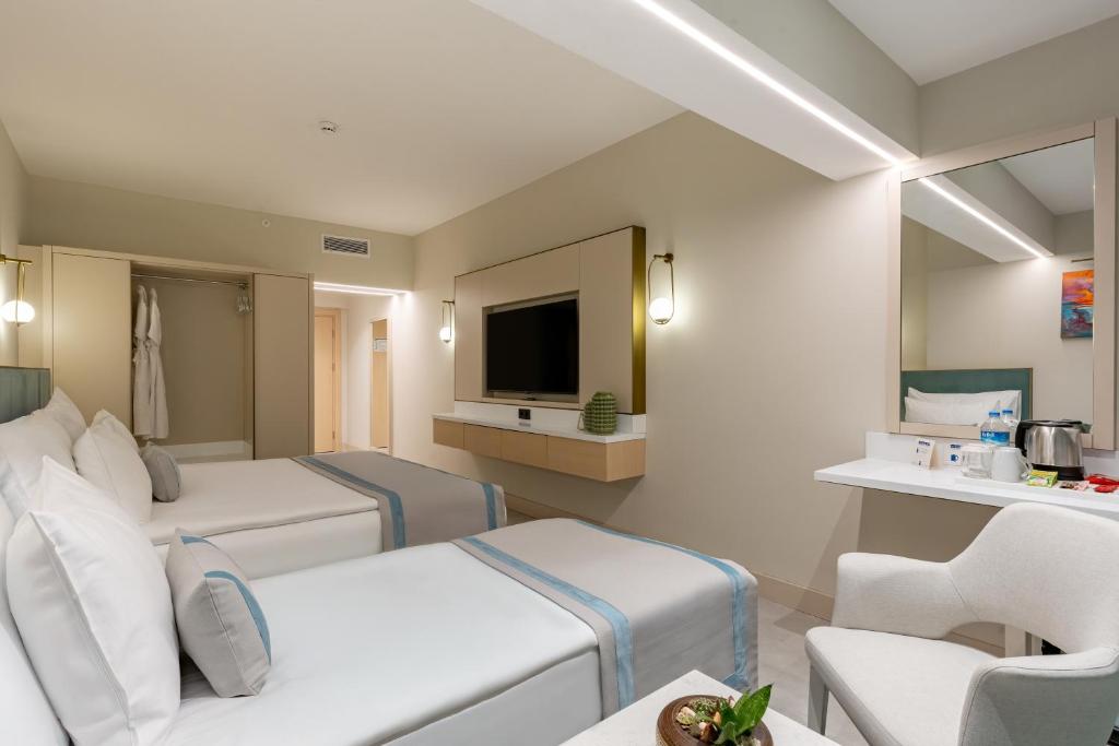 Mūsdienīgs numurs Bergiz Hotels & Resort Kemer ar divām gultām un televizoru.